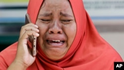 Seorang ibu menangis karena tidak bisa melihat jasad putrinya yang telah dikubur massal.