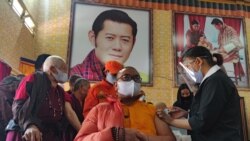 A health worker inoculates a dose of a COVID-19 coronavirus vaccine to a Buddhist monk