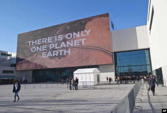 Participants walk past the main entrance of the One Planet Summit, in Boulogne-Billancourt near Paris, France, Dec. 12, 2017.