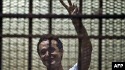 Egyptian political activist Ahmed Douma reacts as he stands behind dock bars during his trial in Cairo on June 3, 2013, on charges of insulting president Mohamed Morsi. 