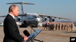 FILE - Russian President Vladimir Putin addresses the troops at the Hemeimeem air base in Syria, Dec. 11, 2017.