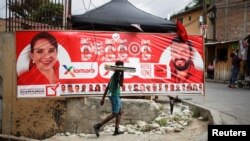 Un joven pasa frente a una pancarta del candidato presidencial del Partido Libre Xiomara Castro antes de las elecciones generales del 28 de noviembre en Tegucigalpa.