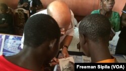 Un humanitaire explique les activités des jeunes aux visiteurs à Bangui, 19 août 2017. (VOA/Freeman Sipila)