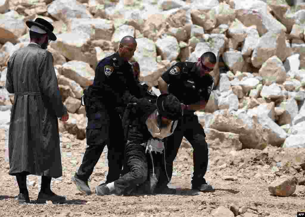 Seorang pria Ultra Ortodoks ditahan oleh polisi Israel dalam sebuah demonstrasi menentang pembangunan unit permukiman baru di sebuah petak tanah yang diyakini sebagai lokasi kuburan Yahudi kuno, di pusat kota Yerusalem.