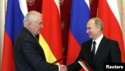 Russian President Vladimir Putin (R) shakes hands with President of the Georgian breakaway region of South Ossetia Leonid Tibilov during a signing ceremony in Moscow, (March 18, 2015.) 