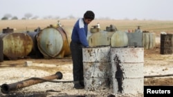 FILE - A youth works at a makeshift oil refinery in the countryside south of Idlib, Syria. 