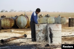 FILE - In this December 2015 photo, a youth works at a makeshift oil refinery in Syria that, according to its owner, gets the crude oil from Islamic State-controlled areas.