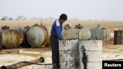 FILE - A youth works at a makeshift oil refinery in Syria that, according to its owner, gets the crude oil from Islamic State-controlled areas.