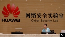 FILE - A receptionist stands at the front counter of the Huawei's Cyber Security Lab at the Huawei factory in Dongguan, China's Guangdong province, March 6, 2019. 