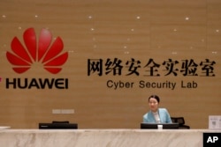 FILE - A receptionist stands at the front counter of Huawei's Cyber Security Lab at the Huawei factory in Dongguan, China's Guangdong province, March 6, 2019.