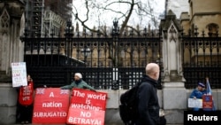 A man passes by pro-Brexit protesters and an anti-Brexit demonstrator outside the Houses of Parliament in London, Britain, March 14, 2019. 