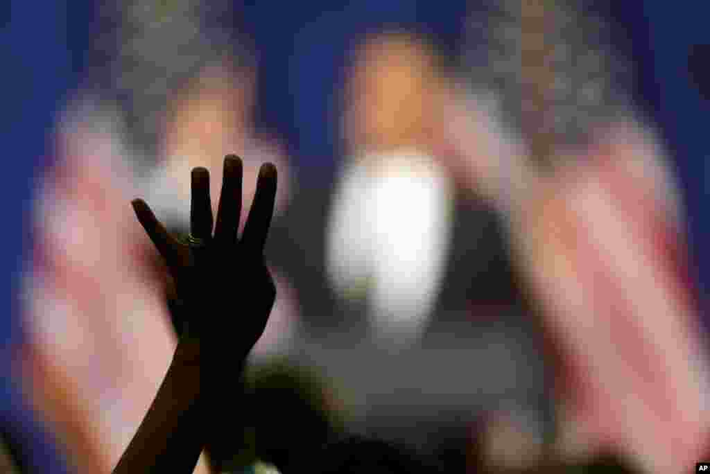 A woman displays four fingers as she chants for four more years while President Barack Obama speaks at a fundraising reception in Baltimore, Maryland, June 12, 2012. (AP) 