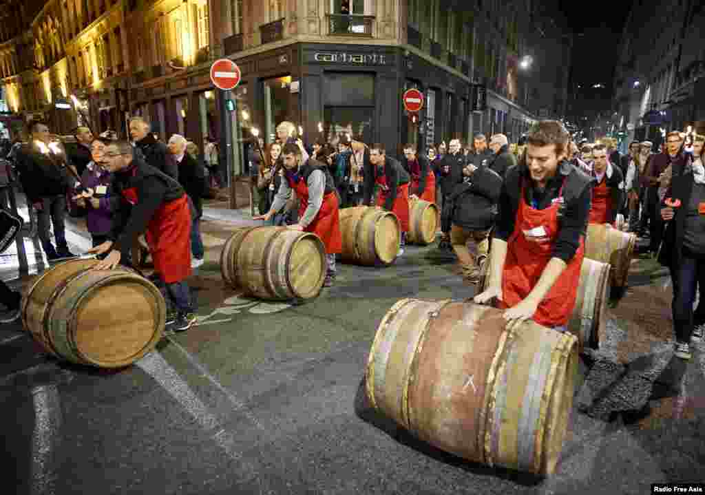 Para pria menggulingkan barel berisi wine Beaujolais Nouveau untuk peresmian penjualan wine 2015 di pusat kota Lyon, Perancis.