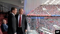 Presiden Rusia Vladimir Putin (kanan) dan Perdana Menteri Rusia Dmitry Medvedev menyaksikan pertandingan pembukaan turnamen Piala Dunia 2018 di Rusia, antara Rusia dan Arab Saudi, di Stadion Luzhniki, Moskow, Rusia, 14 Juni 2018. 