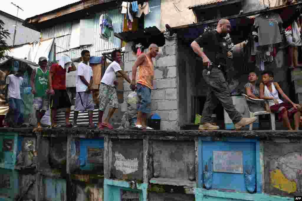 Seorang petugas badan pemberantasan narkoba Filipina menggiring para tersangka narkoba di perkampungan kumuh di Manila.