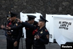 Agentes de policía toman fotos al candidato presidencial Andrés Manuel López Obrador, cuando éste llega a votar en Ciudad de México, el 1 de julio de 2017.