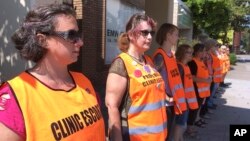 FILE - Escort volunteers line up outside the EMW Women's Surgical Center in Louisville, Ky., July 17, 2017. In a setback for Kentucky's Republican governor, a federal judge has struck down a state law requiring abortion clinics to have written agreements with a hospital and an ambulance service in case of medical emergencies, Friday.