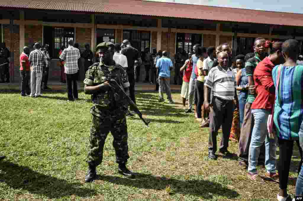 Un garde de sécurité près d'électeurs faisant la queue pour voter dans un bureau de vote à Bujumbura, le 17 mai 2018.
