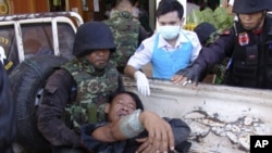 A Thai soldier injured in a fighting with Cambodia is helped by his comrades and a nurse after arriving at a hospital in Phnom Dongrak district of Surin province, northeastern Thailand, Friday, April 22, 2011. Thailand and Cambodia exchanged artillery and
