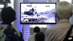 People watch a TV news program showing video footage of a South Korean army tank during a past exercise at Seoul Railway Station in Seoul, South Korea, Wednesday, Aug. 10, 2011. South Korean marines returned fire Wednesday after North Korea launched artil