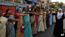 Women raise their hands to take a pledge to fight gender discrimination as they form part of a hundreds kilometer long "women's wall" in Thiruvananthapuram, in the southern Indian state of Kerala, Tuesday, Jan. 1, 2019. (AP Photo/R.S. Iyer)