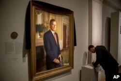 Ameer Hassan of New York stops to sign the condolence book as the official portrait of former President George H.W. Bush is draped in black cloth at the National Portrait Gallery in Washington, Dec. 3, 2018, to mark his passing. Bush will lay in state at the Capitol building this week before being buried in Texas.