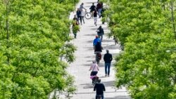 Personas caminan a orillas del río manteniendo la distancia social en Colonia, Alemania, en una soleada tarde del domingo 3 de mayo de 2020.