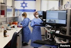 Technicians work at the Maccabi Coronavirus Disease (COVID-19) Public Laboratory of the Health Care Maintenance Organization (HMO), performing various and numerous tests, in Rehovot, Israel, on February 9, 2021. ( REUTERS / Ammar Awad)