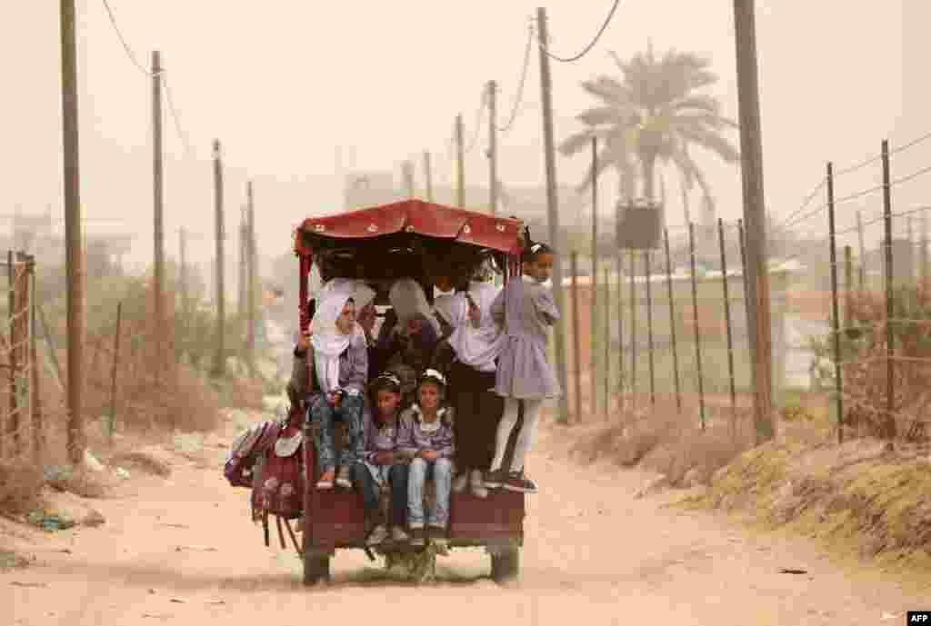 Anak sekolah Palestina naik becak sementara badai pasir sedang berlangsung di Khan Yunis Jalur Gaza selatan. Badai pasir tebal melanda beberapa bagian Timur Tengah dan menyebabkan setidaknya delapan orang tewas dan ratusan menderita masalah pernapasan, dan pemerintah mengingatkan warga untuk tetap tinggal di rumah.