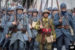 FILE - Men dressed in WWI uniforms march during a parade, part of a reconstruction of the WWI battle of Verdun, Aug. 25, 2018, in Verdun, eastern France.
