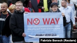 FILE - Supporters of the German far-right National Democratic Party (NPD) hold a placard during an anti-immigration march in Riesa, Germany, Sept. 9, 2015. 