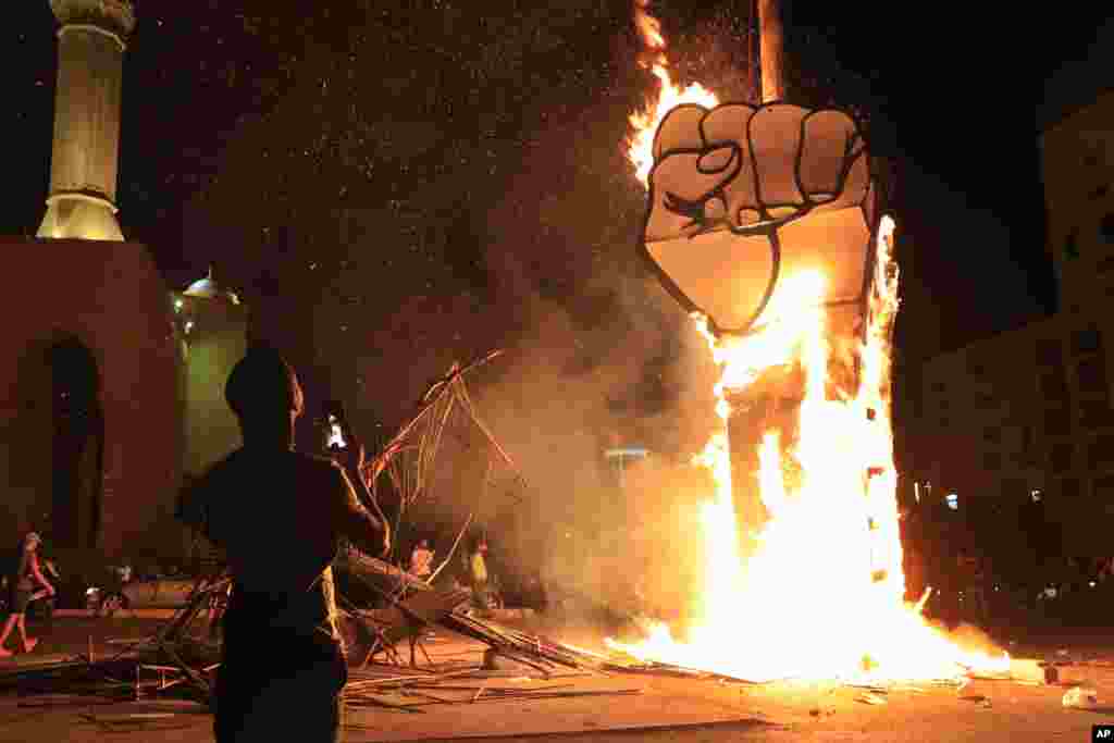 A protester takes pictures of a protest symbol that was set on fire by the supporters of former Lebanese Prime Minister Saad Hariri, after a small demonstration had denounced the naming of Hariri as a potential candidate as the country's new prime ministe