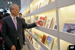 中國駐美大使崔天凱在紐約書展的中國攤位拿起一本論述中共在中國為何成功、如何成功的書（2015年5月27日）