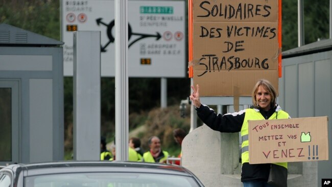 Un manifestante sostiene una pancarta que dice "Todos juntos, pónganse sus chalecos amarillos y vengan", en Biarritz, suroeste de Francia.