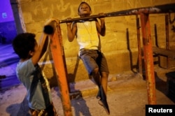 A boy does pull-ups from a metal bar outside the Luta pela Paz (Fight for Peace) boxing school, in the Mare favela of Rio de Janeiro, Brazil, June 2, 2016.
