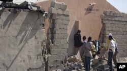 People stand near a damaged wall of a church after an explosion in Jajeri district in Nigeria's northeastern city of Maiduguri, December 23, 2011