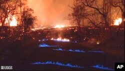 This photo was taken from video by the U.S. Geological Survey. It shows blue flames of methane gas erupting through cracks on Kahukai Street in the Leilani Estates neighborhood of Pahoa on the island of Hawaii, May 23, 2018. 