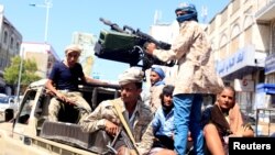 FILE - Government soldiers ride on the back of a patrol truck on a street where people demonstrated against the deterioration of Yemen's economy and the devaluation of the local currency.