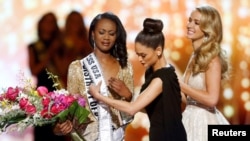 Deshauna Barber (L) of the District of Columbia reacts as Miss Universe 2015 Pia Wurtzbachshe gives her the winner's sash during the 2016 Miss USA pageant at the T-Mobile Arena in Las Vegas, Nevada, U.S., June 5, 2016.