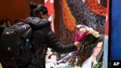 Una mujer deja flores junto a un libro de condolencias antes de una ceremonia en la Universidad de Carleton, el miércoles 15 de enero de 2020, en memoria de un estudiante fallecido en el avión de Ukraine International Airlines estrellado en Teherán. (Canadian Press via AP)