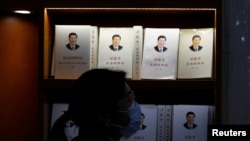Una mujer con mascarilla camina frente a un expositor donde se puede ver un libro sobre el presidente Xi Jinping, en Beijing, el 1 de marzo de 2021.