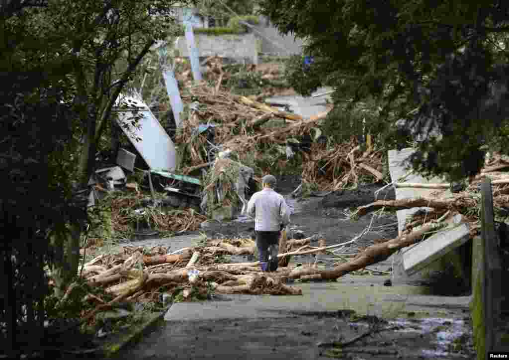 A man walks near collapsed houses following a landslide caused by Typhoon Wipha on Izu Oshima island, south of Tokyo, in this photo taken by Kyodo, Oct. 16, 2013.