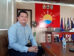 Kong Monika, president of the Khmer Will Party, sits in front of the party's logo while being interviewed by VOA Khmer at its headquarters in Phnom Penh, Cambodia, April 7, 2020. (Aun Chhengpor/VOA Khmer)