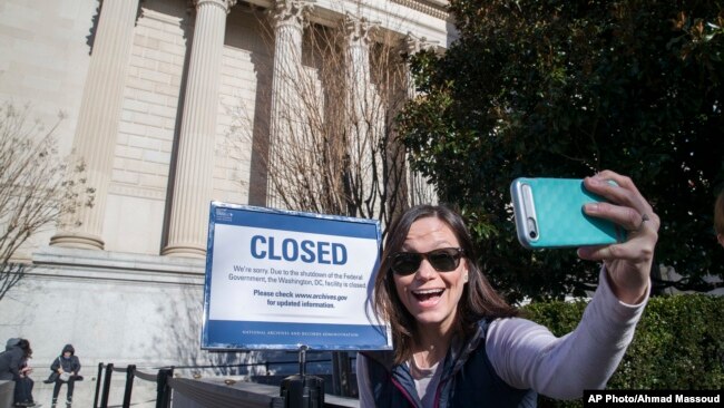 Jamie Parrish, from Minneapolis, takes a selfie in front of the closed sign at the National Archives, Dec. 22, 2018, in Washington. Congress' inability to approve a funding measure that includes money for President Donald Trump's proposed U.S.-Mexico border wall.