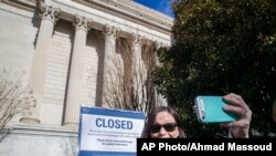 Jamie Parrish, ki soti Minneapolis, ap pran yon selfie ak ansèy ki anonse gouvènman fèmen e ki devan achiv Nasyonal la nan Washington DC. 22 desanm 2018. 