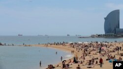 FILE - In this May 25, 2016 photo, people sunbathe at the Barceloneta beach in Barcelona, Spain.