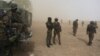 Cameroonian soldiers from the Rapid Intervention Brigade stand guard amidst dust kicked up by a helicopter in Kolofata, Cameroon, March 16, 2016. Cameroon has joined the multinational force to combat Boko Haram.