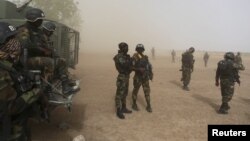 Cameroonian soldiers from the Rapid Intervention Brigade stand guard amidst dust kicked up by a helicopter in Kolofata, Cameroon, March 16, 2016. Cameroon has joined the multinational force to combat Boko Haram.