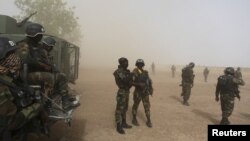 FILE - Cameroonian soldiers from the Rapid Intervention Brigade stand guard amidst dust kicked up by a helicopter in Kolofata, Cameroon, March 16, 2016. 