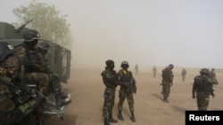 FILE - Cameroonian soldiers from the Rapid Intervention Brigade stand guard amidst dust kicked up by a helicopter in Kolofata, Cameroon.